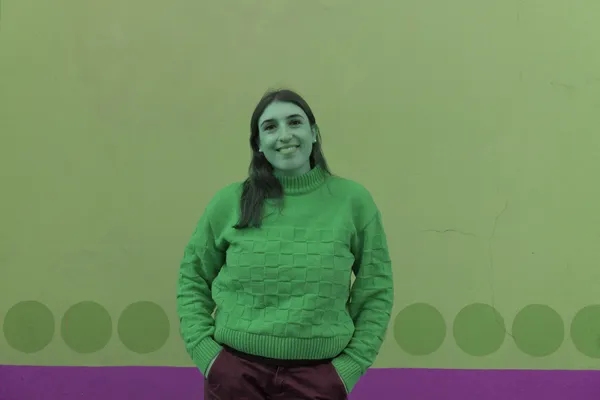 Donna sorridente con maglione a quadri davanti a un muro a pois