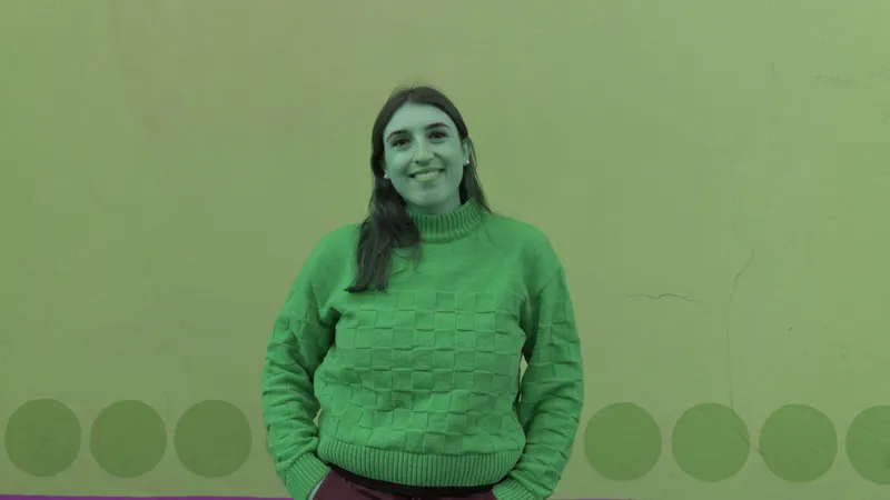 Donna sorridente con maglione a quadri davanti a un muro a pois