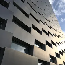 Facciata angolata in cemento del termovalorizzatore, con finestre sfalsate sotto un cielo nuvoloso