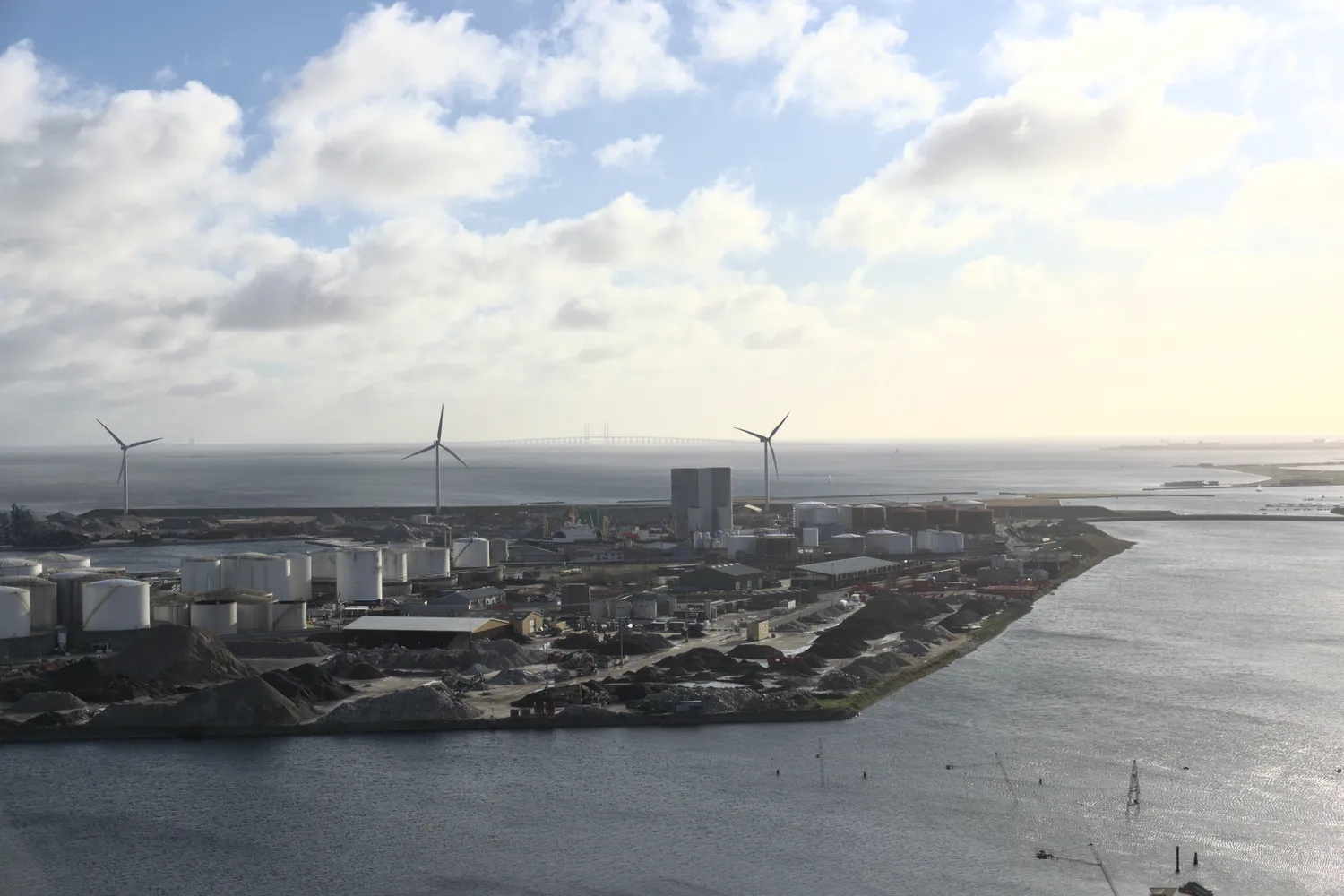Veduta del porto industriale di Refshaleøen con turbine eoliche e ponte sullo sfondo
