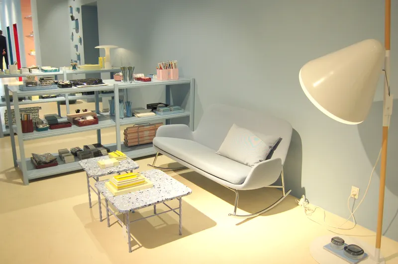 Interno del negozio Normann Copenhagen con divano grigio, lampada da terra e scaffali