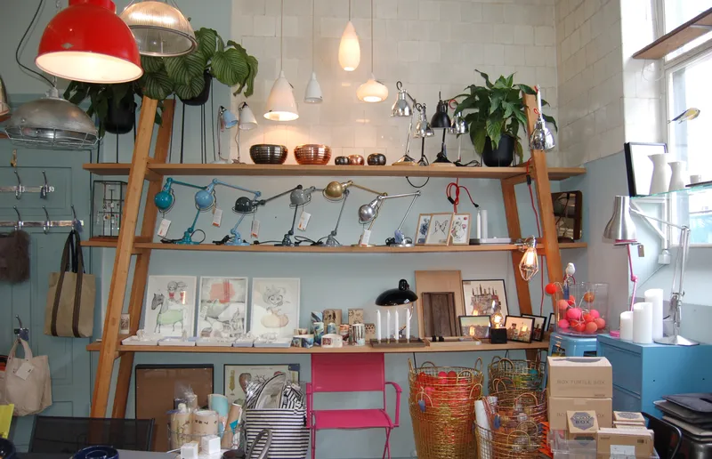 Interno del negozio di design RAMBOW con lampade, piante e ceste sugli scaffali