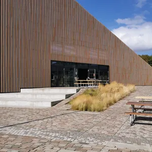Edificio rivestito in listelli di legno con tetto inclinato e piazza acciottolata
