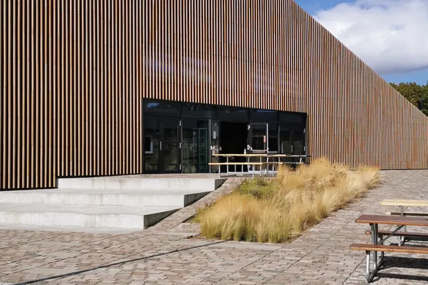 Edificio rivestito in listelli di legno con tetto inclinato e piazza acciottolata