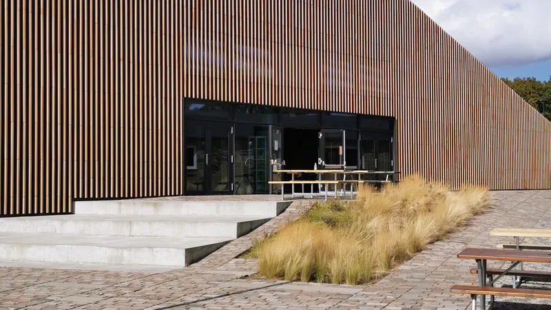 Edificio rivestito in listelli di legno con tetto inclinato e piazza acciottolata