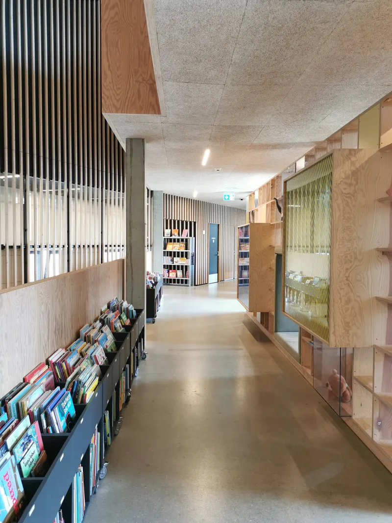 Corridoio della biblioteca Tingbjerg con scaffali bassi di libri per bambini