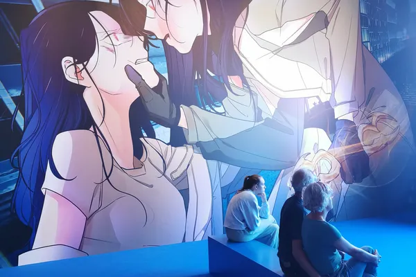 Visitatori seduti davanti a un grande murale illuminato in blu