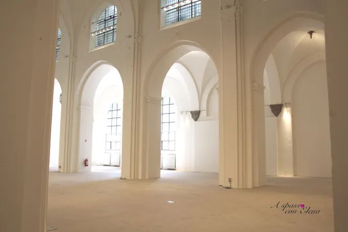 Sala espositiva bianca della kunsthal con archi a volta e alte finestre