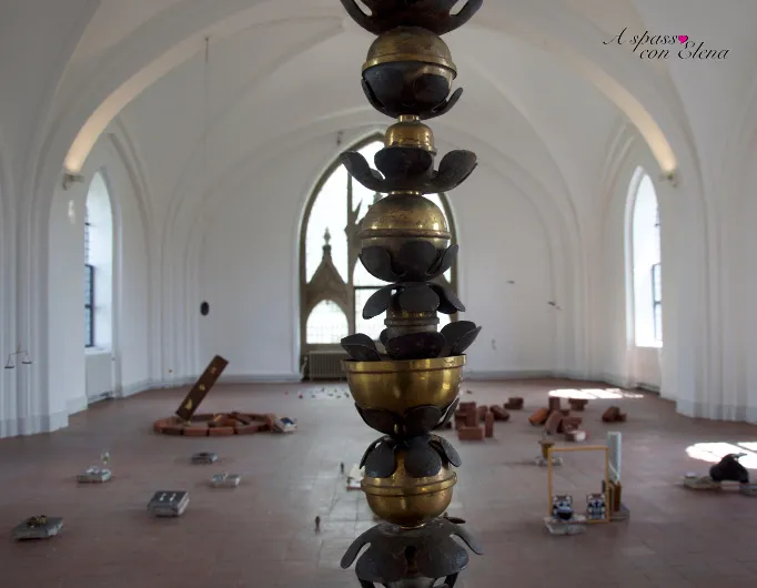 Scultura di sfere dorate e foglie in sala bianca con volte a crociera