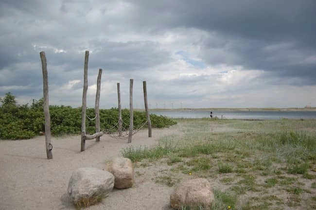 La spiaggia di Amager con pali di legno e amaca in una giornata nuvolosa