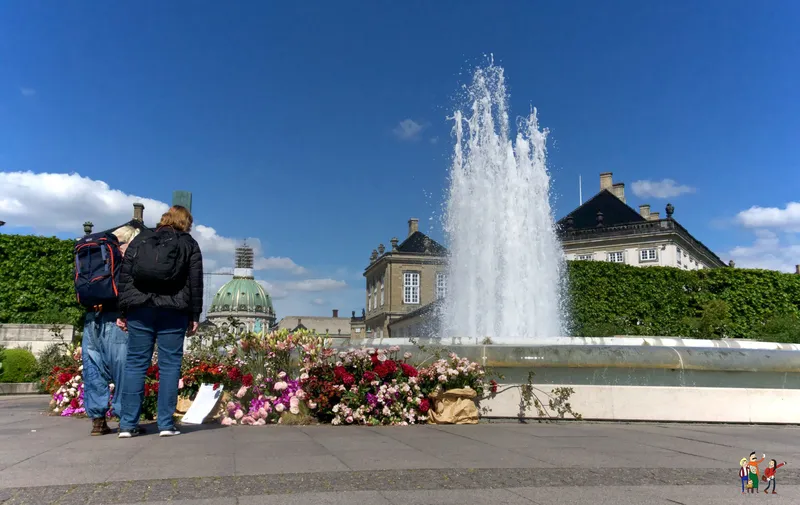 Coppia osserva una fontana e aiuole fiorite ad Amalienborg