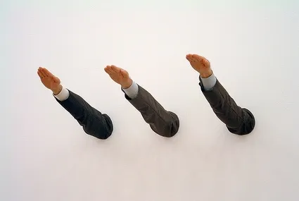 Ave Maria di Maurizio Cattelan: tre braccia in maniche da abito sporgono dal muro bianco salutando