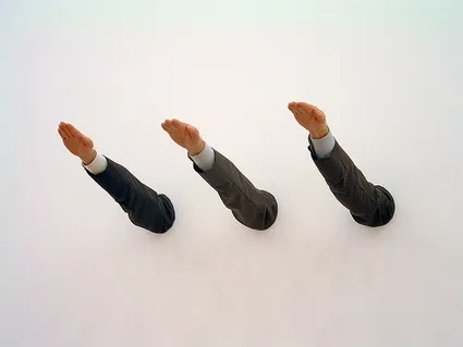 Ave Maria di Maurizio Cattelan: tre braccia in maniche da abito sporgono dal muro bianco salutando