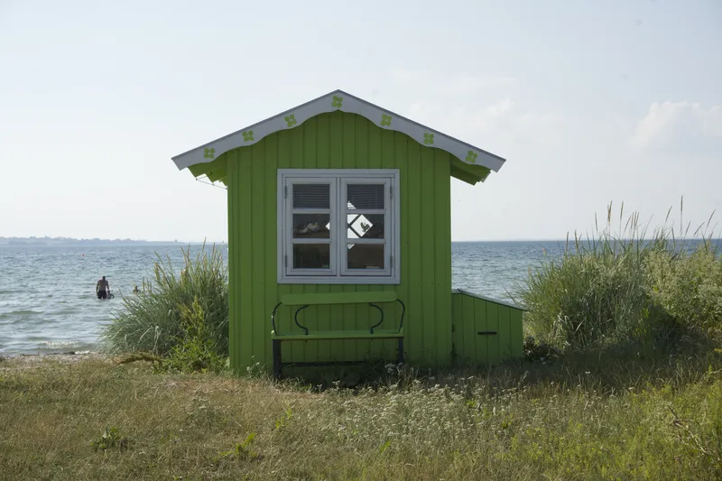 Iconica badehus verde sulla spiaggia di Ærø, mare sullo sfondo