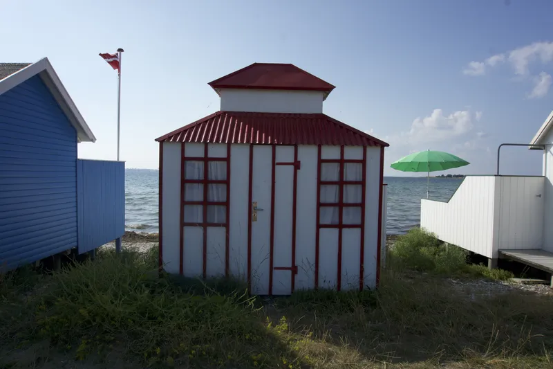 Badehus bianca e rossa con bandiera danese sulla spiaggia di Ærø