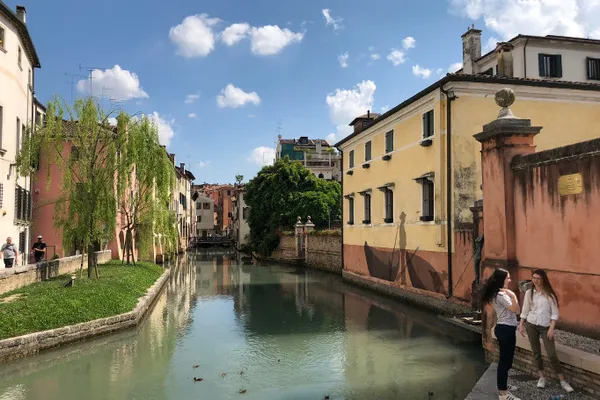 Stretto canale di Treviso fiancheggiato da case storiche e salici piangenti
