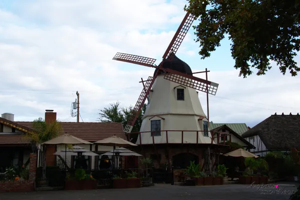 Mulino a vento bianco con ristorante e ombrelloni nel cortile a Solvang