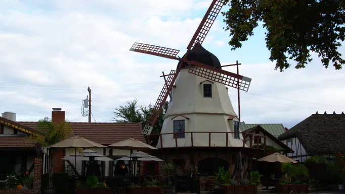 Mulino a vento bianco con ristorante e ombrelloni nel cortile a Solvang