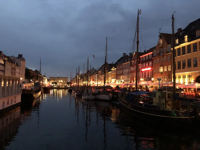 Copenhagen's old harbour Nyhavn at dusk with sailboats and lit houses