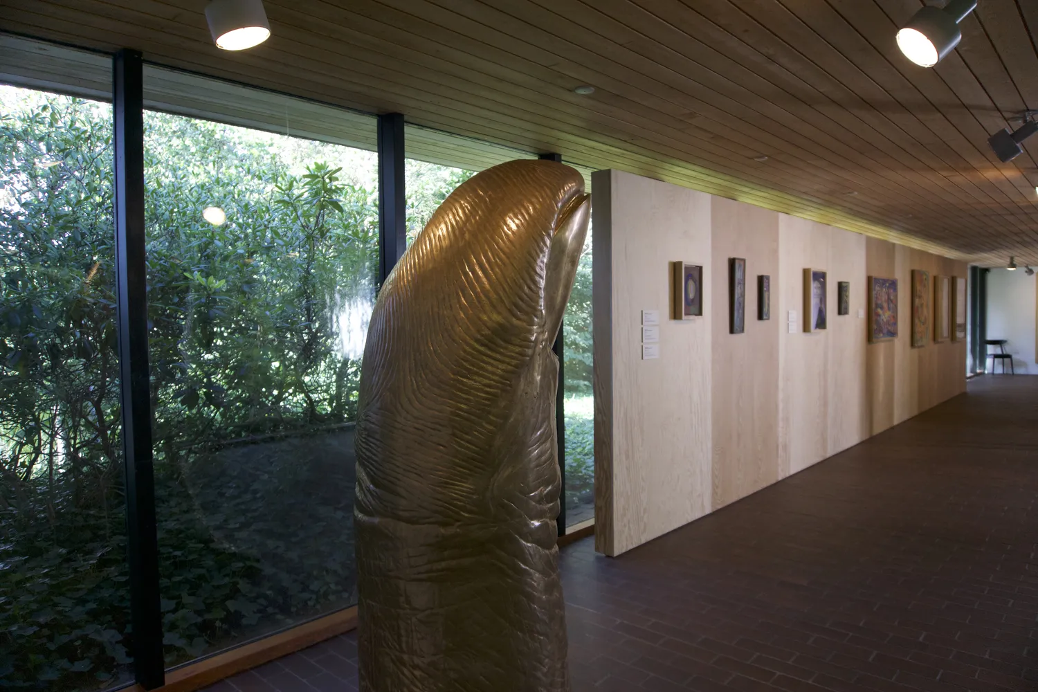 Scultura dorata in una sala del Louisiana Museum of Modern Art con vetrate sul giardino