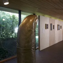 Scultura dorata in una sala del Louisiana Museum of Modern Art con vetrate sul giardino