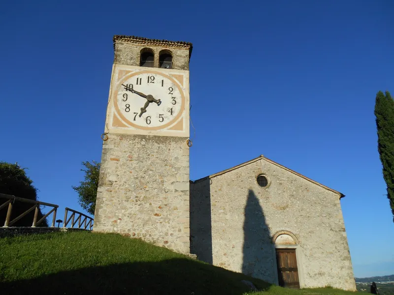 Church of San Vigilio in Col San Martino with bell tower and clock on a hill