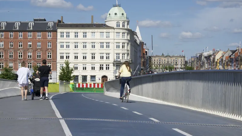 Ciclista e pedoni su un ponte azzurro verso palazzi storici