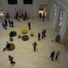 Atrio luminoso di un museo con visitatori e sedute rotonde colorate