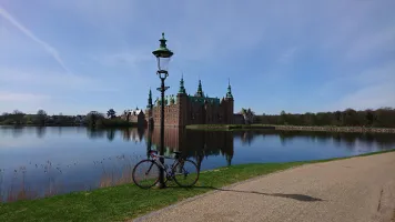Castello di Frederiksborg riflesso nel lago con bicicletta in primo piano