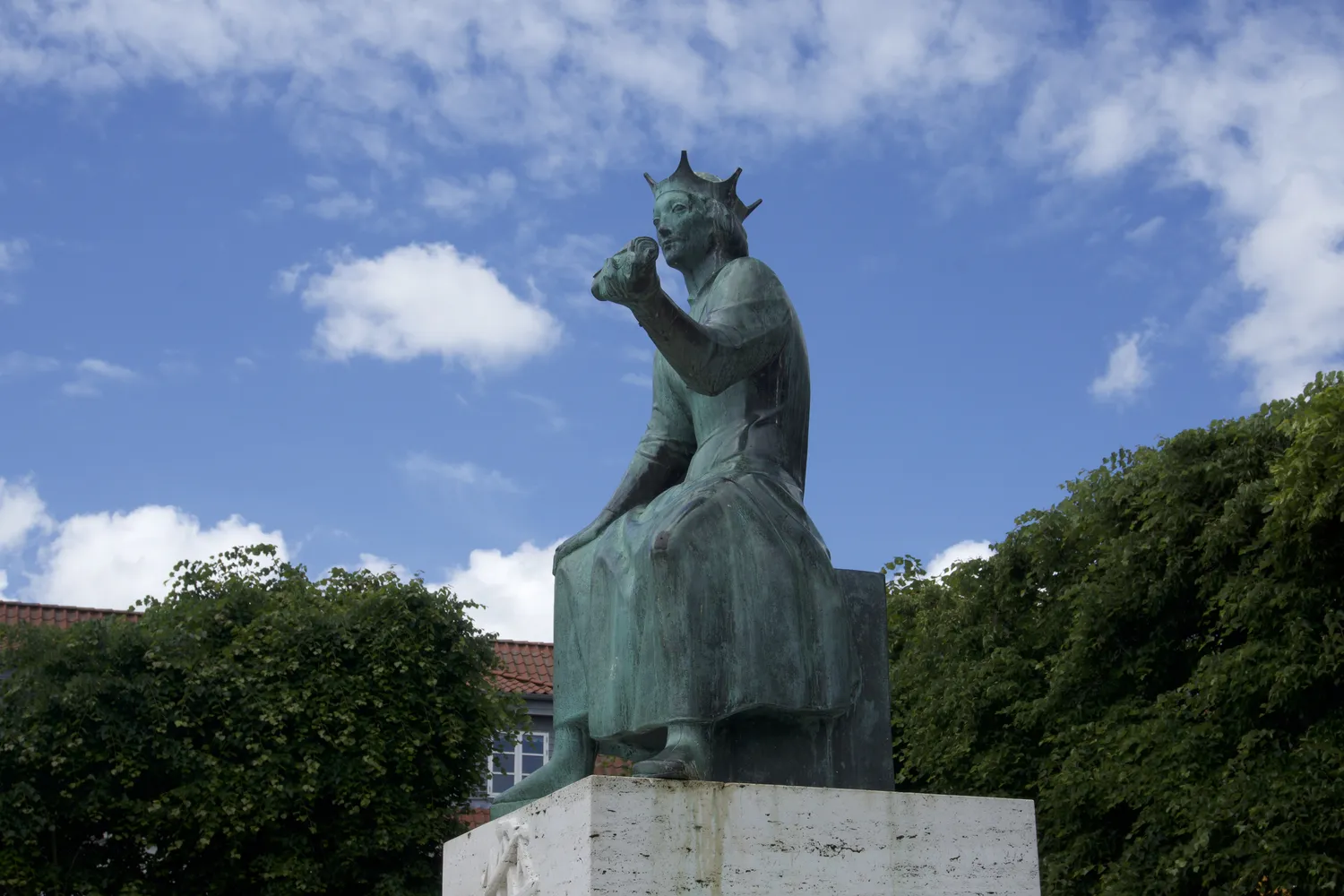Statua bronzea di re con corona seduto, contro un cielo azzurro