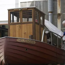Uomo copre con un telo una barca di legno chiamata Helsingor