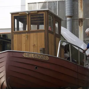 Uomo copre con un telo una barca di legno chiamata Helsingor