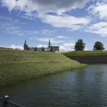 Il Castello di Kronborg con torri verdi oltre il fossato e gli argini erbosi