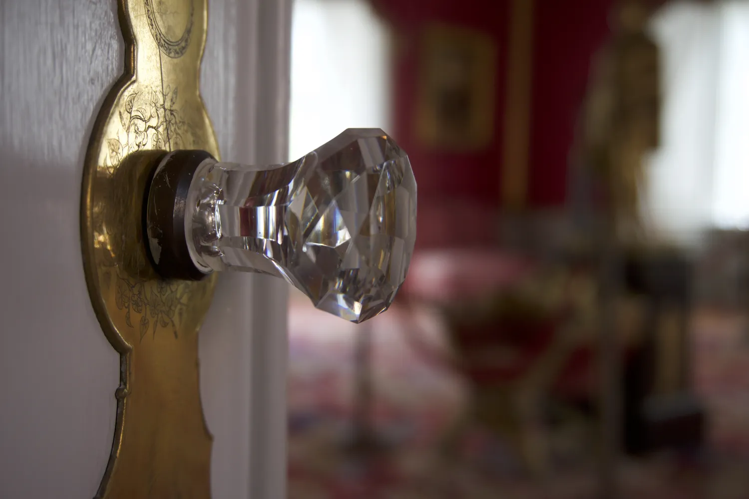 Pomello di vetro sfaccettato su porta con placca dorata incisa