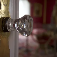Pomello di vetro sfaccettato su porta con placca dorata incisa