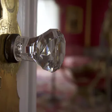 Pomello di vetro sfaccettato su porta con placca dorata incisa