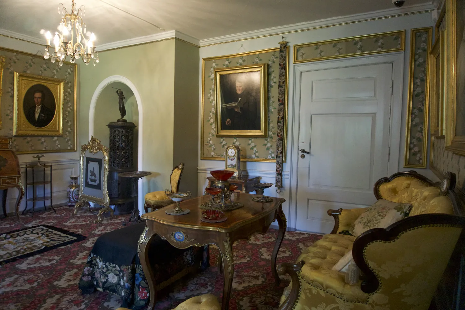 Elegante salotto storico con lampadario, ritratti e divano dorato