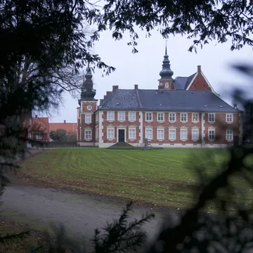Il castello di Jægerspris in mattoni rossi con torrette tra i rami