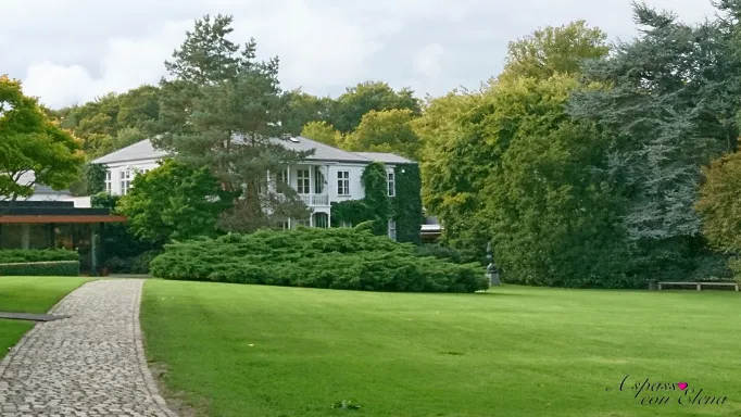 Villa bianca coperta d'edera con prato e vialetto acciottolato al Museo Louisiana