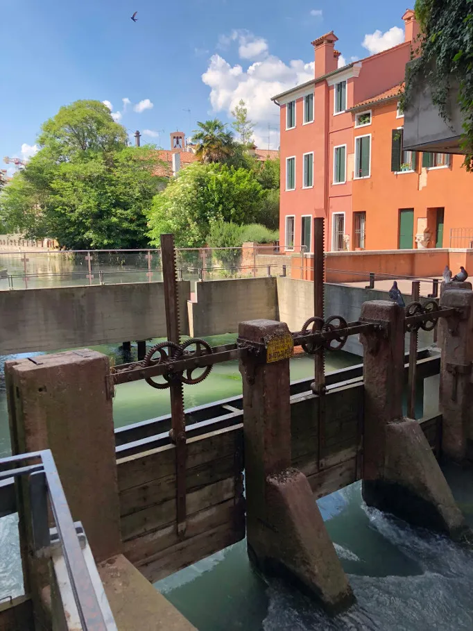 Canal sluice gate with metal gears and colorful Treviso houses