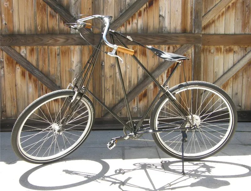 Bicicletta Pedersen nera dalle linee eleganti appoggiata a un portone