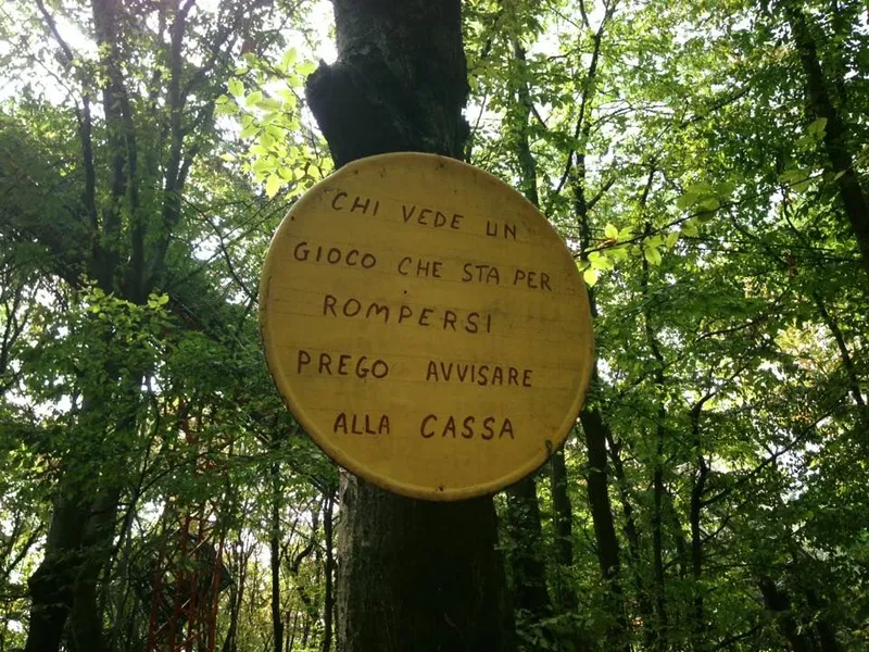 Round wooden hand-lettered sign hung on a tree at the Ai Pioppi park