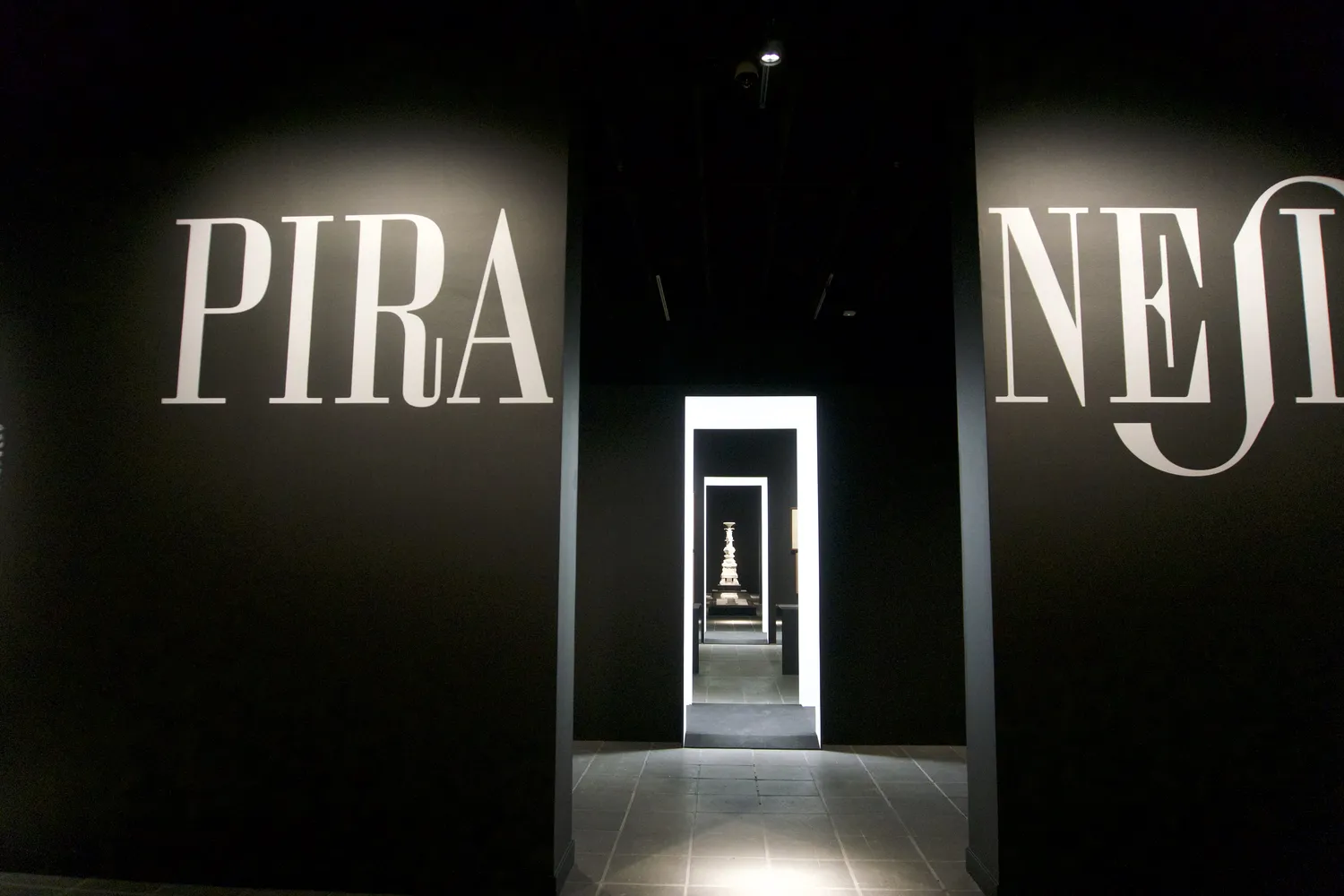 Ingresso buio di una mostra su Piranesi con grandi scritte sulle pareti