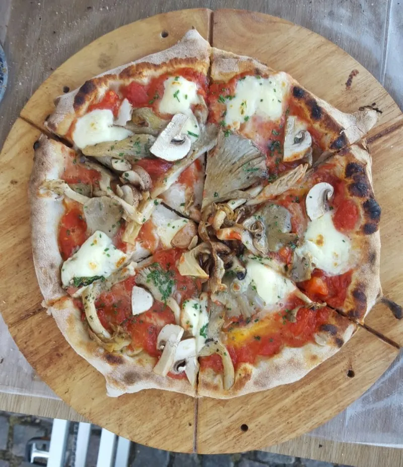 Pizza ai funghi con pomodoro e mozzarella su tagliere di legno