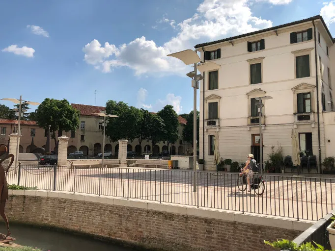 Square with arcade and historic buildings along a canal in Treviso