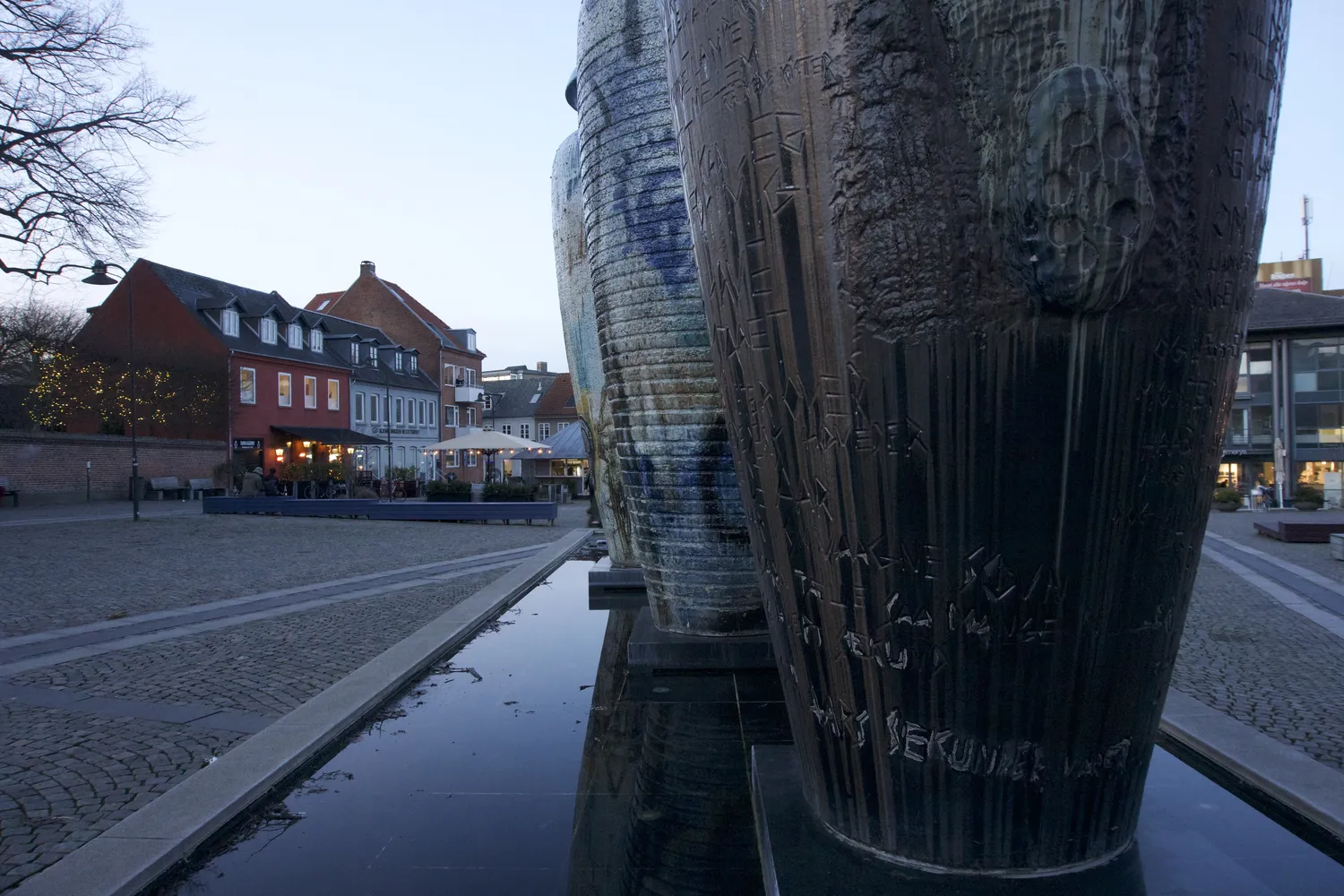 Grandi vasi di ceramica accanto a una vasca d'acqua in una piazza al tramonto