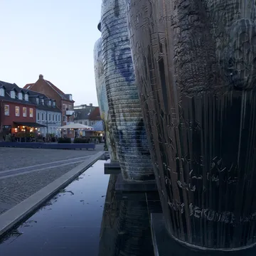 Grandi vasi di ceramica accanto a una vasca d'acqua in una piazza al tramonto