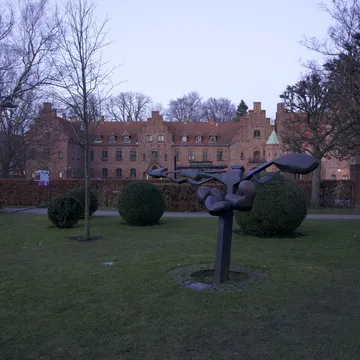 Scultura moderna in un giardino davanti a un edificio storico in mattoni