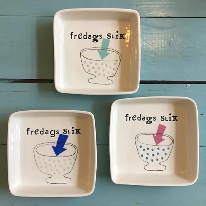 Tre ciotoline bianche con scritta fredags slik su legno azzurro
