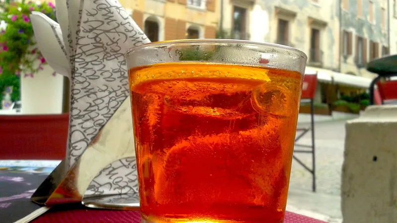 Bicchiere di Spritz veneto arancione su un tavolino in una piazza